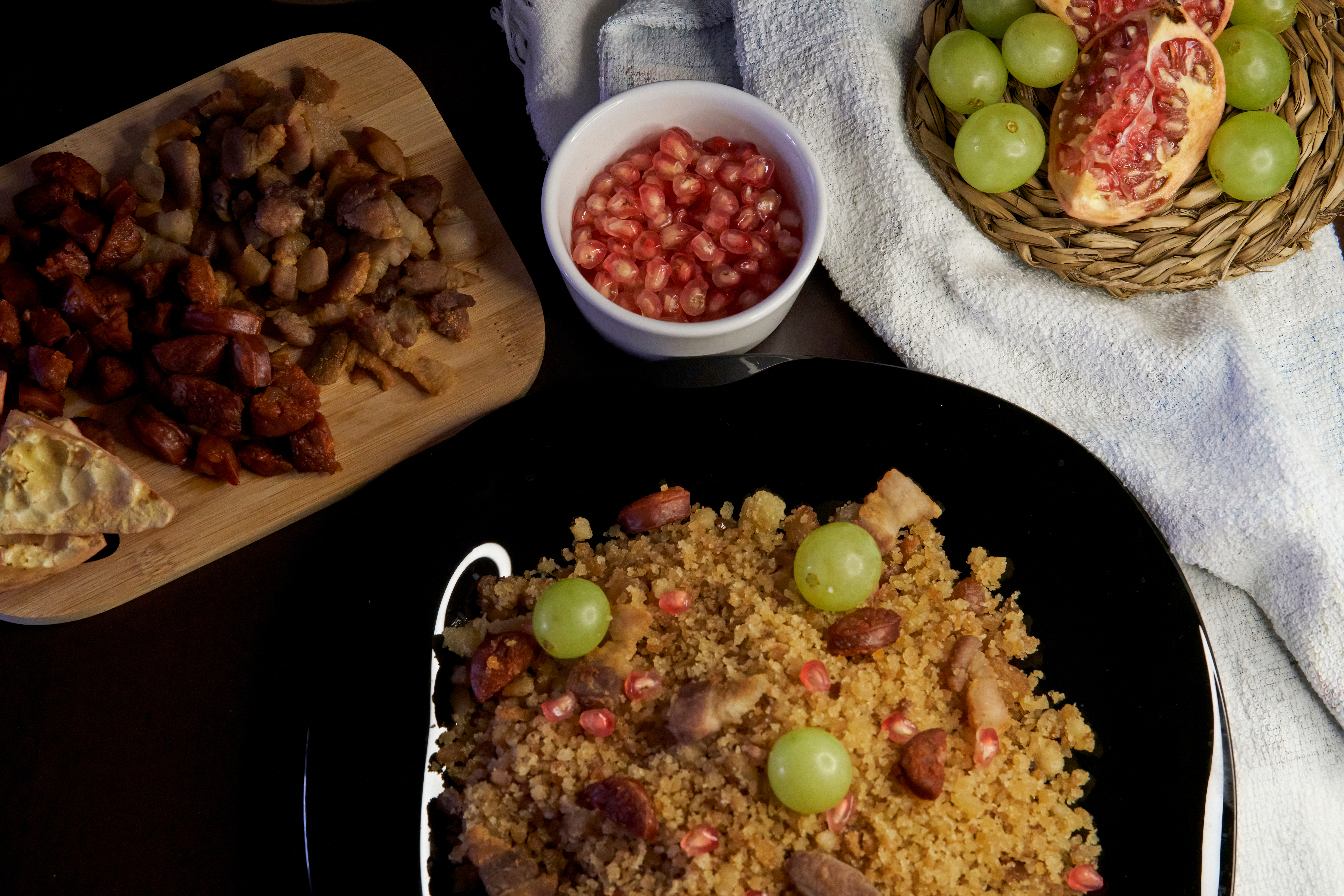 Mesa con distintos platos: Migas, carne, granada y uvas